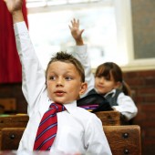 Young Boy at School Raising His Hand to Answer in Private School Class